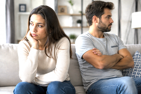 ¿Por qué repetimos el mismo patrón de pareja? Pareja distanciada sentada en un sofá tras una discusión, representando los patrones de pareja que se repiten en las relaciones.